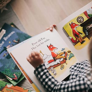 A child and adult reading an illustrated storybook together in a cozy setting.